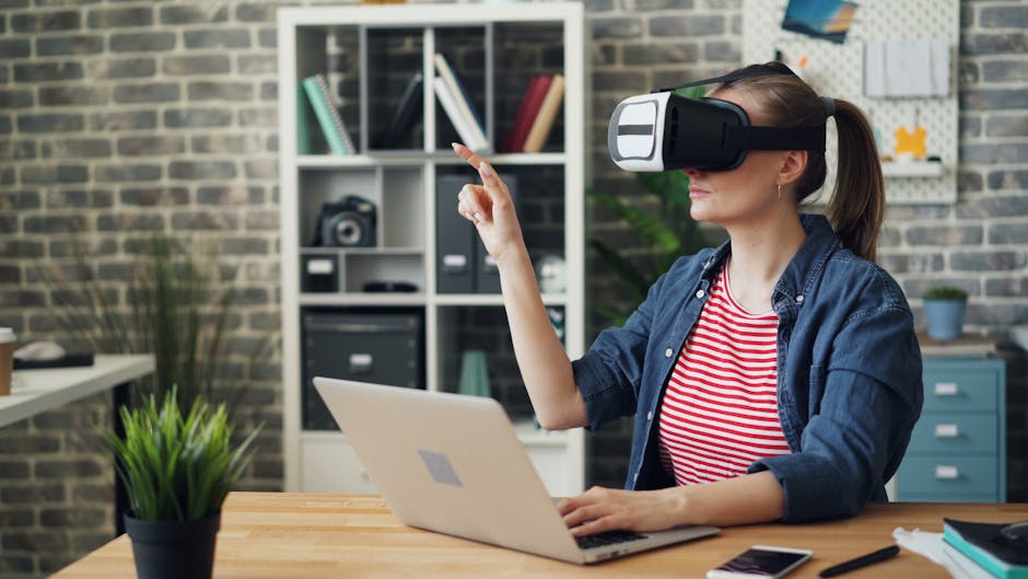 A woman using a VR headset while working on a laptop, exploring virtual reality in a modern office setting